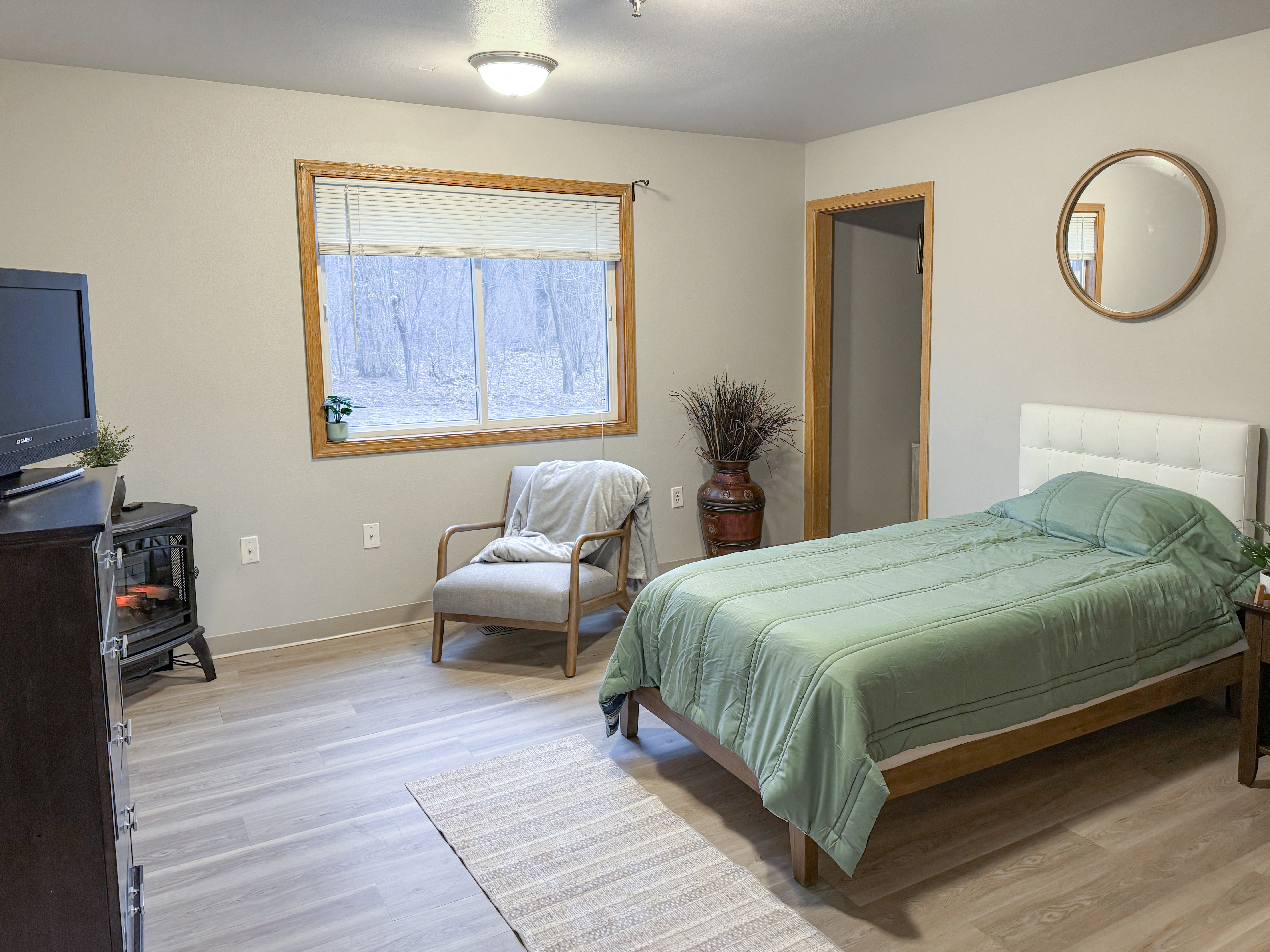 A bedroom with a bed, chair, and window.